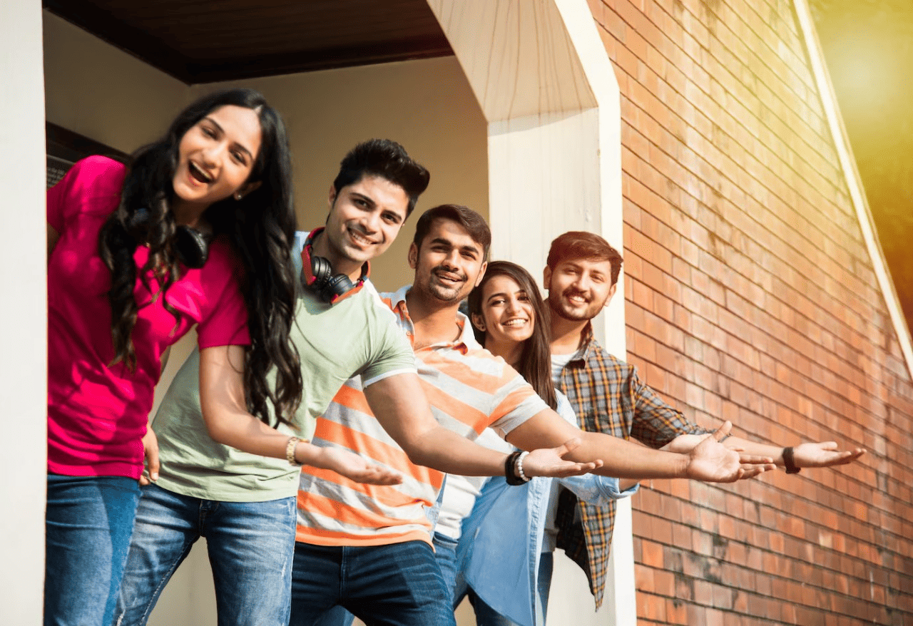 Group of happy international students posing outdoors near university building